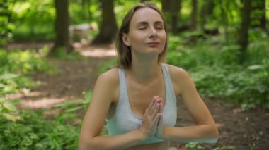 Ormanda yoga yapan bir kadın. Genç kız doğada meditasyon yapıyor, ağır çekimde. Zindelik kavramı, sağlıklı yaşam tarzı.