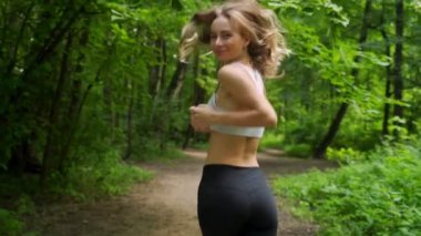 Genç sporcu kadın ormanda koşuyor.