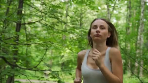 Jonge vrouwelijke atleet loopt door het bos — Stockvideo