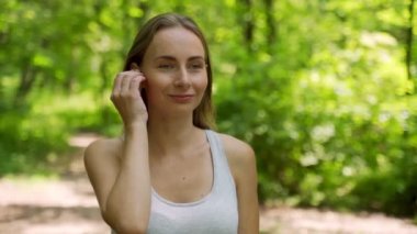 Genç kız kulaklık takıyor ve yazın parkta koşuyor, sağlıklı bir yaşam tarzı..