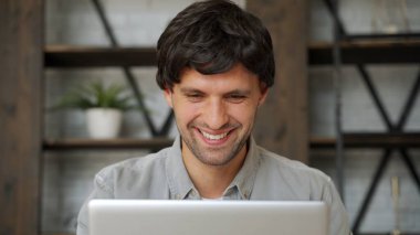 Mutlu galip. Genç heyecanlı adam koltukta otururken dizüstü bilgisayar kullanıyor..