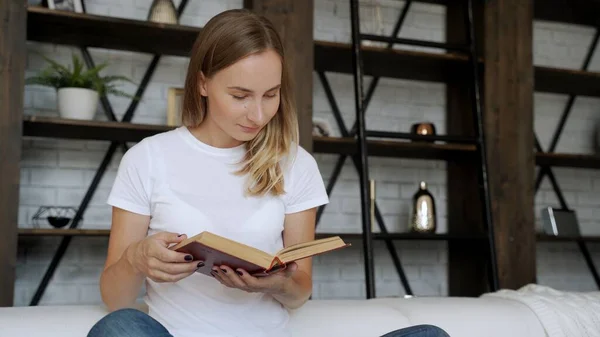 Красивая молодая женщина читает книгу на диване. — стоковое фото
