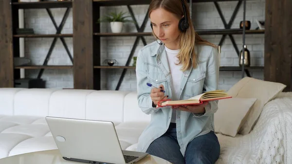 Nő alkalmazott vezeték nélküli fülhallgató beszélni video hívás, webkonferencia kollégáival, női dolgozó headset óra webinar modern laptop otthon — Stock Fotó