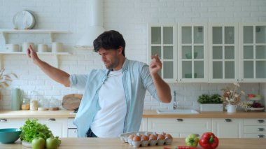 Genç ve komik bir adam sabah mutfakta dans ediyor.
