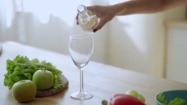 Mutfağındaki bir şişeden bardağa taze su döken bir kadının yakın çekimi..