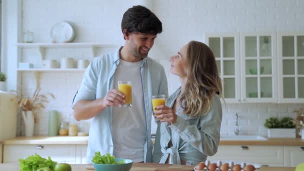 Gelukkig koppel drinken sinaasappelsap in de keuken. — Stockvideo