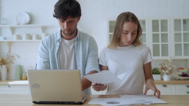 Familia joven con problemas de deuda. Mujer y hombre estudiando banco de papel mientras administran el presupuesto doméstico juntos en el interior de la cocina — Vídeos de Stock