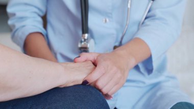 Doktor yaşlı hastaların ellerini tutar ve onu sakinleştirir.