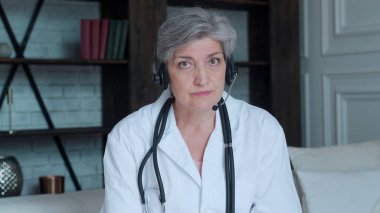 Kulaklık takan yaşlı doktor kadın terapist görüntülü konuşma yoluyla sanal hastaya danışmanlık yapıyor..