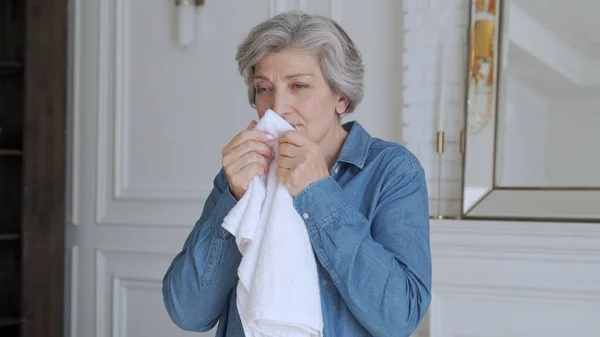 Uma mulher idosa cheira uma toalha fresca em casa — Fotografia de Stock