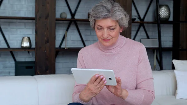 Mujer mayor que usa un dispositivo de tableta en casa — Foto de Stock