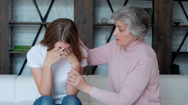 Una madre de mediana edad y una hija adulta están sentadas en el sofá. Mamá calma a su hija, la ayuda a través de un mal divorcio para romper con su novio — Foto de Stock