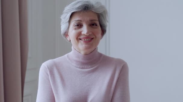 Bella vecchia donna con i capelli grigi sorride in piedi a casa — Video Stock