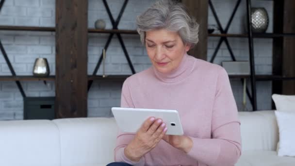 Oudere vrouw die thuis een tabletgadget gebruikt — Stockvideo