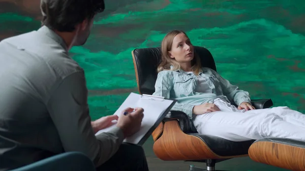 A mental health specialist takes notes when a patient talks about problems while sitting in a chair — Stock Photo, Image