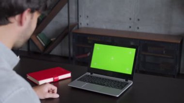 Ofiste yeşil ekranlı bir bilgisayarda iş adamı görüntülü sohbeti. Şirket çalışanı ev ofisteki dizüstü bilgisayardan videoyu arıyor.. 