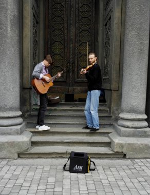 04.18.2019 Kiev Ukrayna. İki sokak müzisyeni. Bir gitarist ve sinagogun kapılarının arka planında ikinci kemancı.