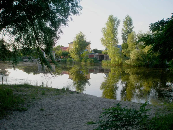 Yaz mavisi gökyüzünün arka planında akşam manzarası, nehir ve ağaçlar.