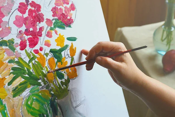 Painting on canvas.  An artist\'s hand with a brush paints a picture.