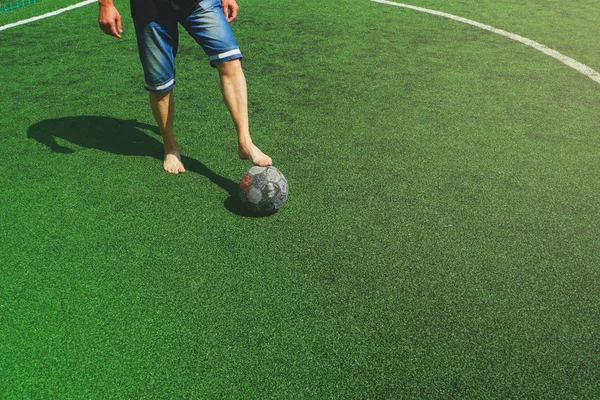 ヨーロッパのサッカー スポーツシューズと新しいボールのためのお金の欠如 緑の新しい人工フィールドで 靴と古いボールのないサッカー選手 — ストック写真