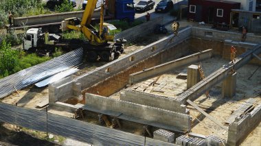 Bir vinç ve inşaatçılar yardımıyla evin inşaatı sırasında beton kiriş montajı.08,20,2019 Kiev Ukrayna.
