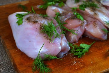    Karabiber baharat ve maydanoz ve dereotu yeşillik ile kahverengi ahşap mutfak tahtası üzerinde Çiğ tavuk eti.   