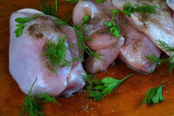    Karabiber baharat ve maydanoz ve dereotu yeşillik ile kahverengi ahşap mutfak tahtası üzerinde Çiğ tavuk eti.   