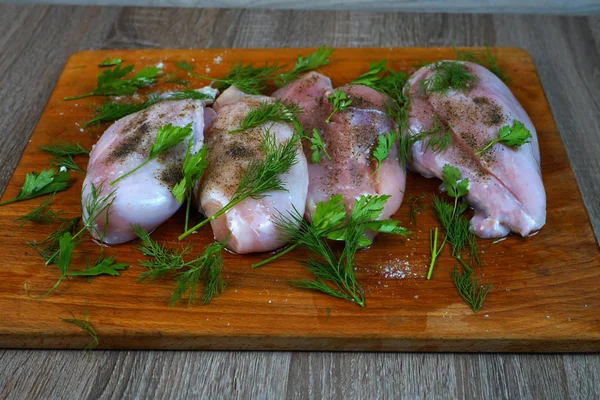    Karabiber baharat ve maydanoz ve dereotu yeşillik ile kahverengi ahşap mutfak tahtası üzerinde Çiğ tavuk eti.   