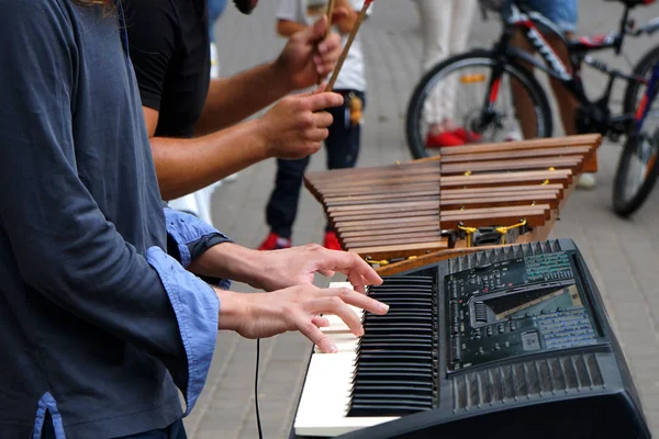 Two musicians on the street on a warm summer day. Digital piano and the traditional Xylophone. People around listen to music .