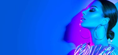 Renkli parlak neon ışıklar içinde moda modeli esmer kadın stüdyoda poz. Trendy parlayan makyaj, metalik gümüş dudaklar.