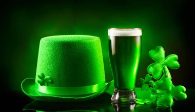 Aziz Patrick Günü. Yeşil bira pint ve koyu yeşil arka plan üzerinde leprechaun şapka, shamrock yaprakları ile dekore edilmiştir. Geleneksel İrlanda festivali