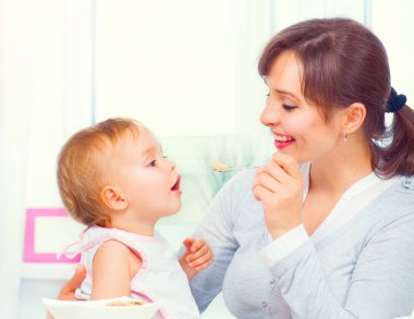 Anne küçük kızını kaşıkla besliyor. Bebek maması. Sağlıklı fa