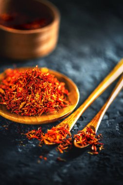 Safran baharatları. Bir ahşap kase siyah taş masada safran ve 