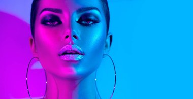 Renkli parlak neon ışıklar içinde moda modeli esmer kadın stüdyoda poz. Trendy parlayan makyaj, metalik gümüş dudaklar.