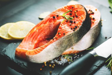 Somon. Siyah arduvaz üzerinde otlar ve limon ile Çiğ alabalık balık biftek