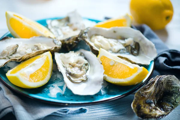 新鲜牡蛎特写在蓝色盘 服务表与牡蛎 柠檬在餐厅 — 图库照片