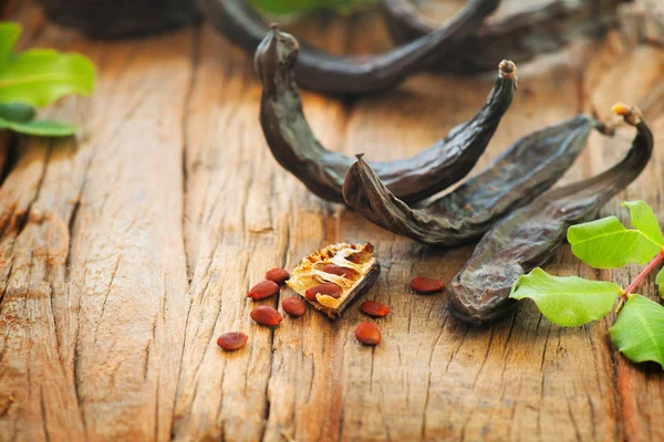 Carob. Healthy organic sweet carob pods with seeds and leaves on — Stock Photo, Image