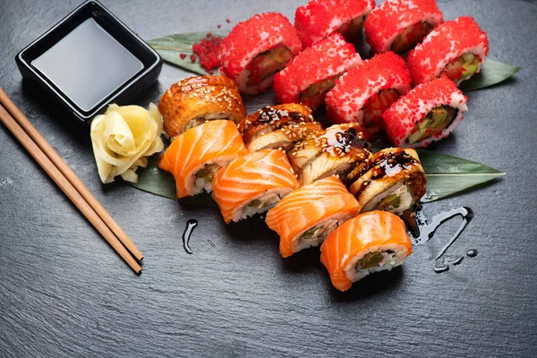 寿司卷特写 餐厅的日式食品 加州寿司卷设置鲑鱼 蔬菜和飞鱼鱼子酱在黑色石板背景 — 图库照片