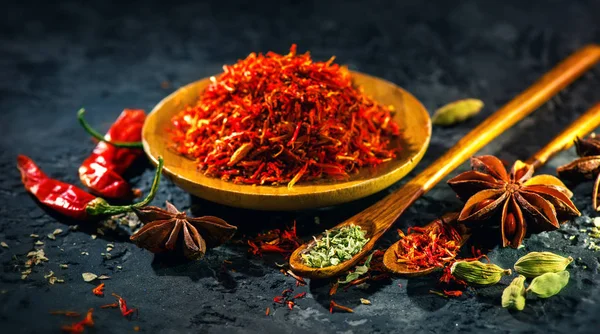 Saffron. Várias especiarias indianas na mesa de pedra preta. Especiarias e h — Fotografia de Stock