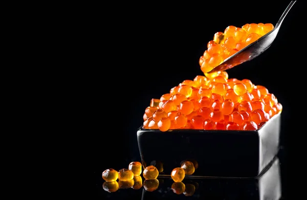Caviar numa colher. Caviar de salmão em uma tigela sobre fundo preto — Fotografia de Stock