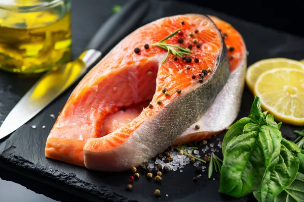 Lachs. rohe Forellenfischsteak mit Kräutern und Zitrone auf schwarzem Schiefer — Stockfoto