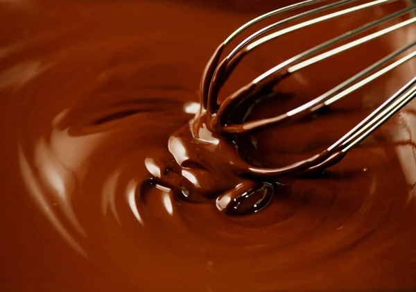 Шоколад. Смешивание расплавленного тёмного шоколада с венчиком. Крупный план — стоковое фото