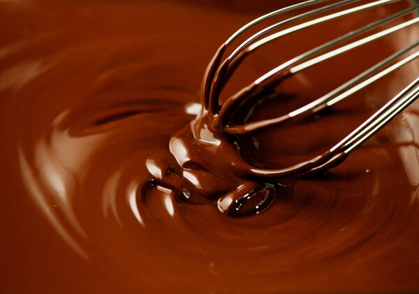 Chocolate. Mixing melted dark chocolate with a whisk. Closeup of