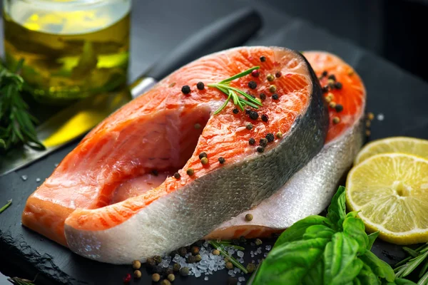 Zalm. Rauwe forel vis Steak met kruiden en citroen op zwarte leisteen — Stockfoto