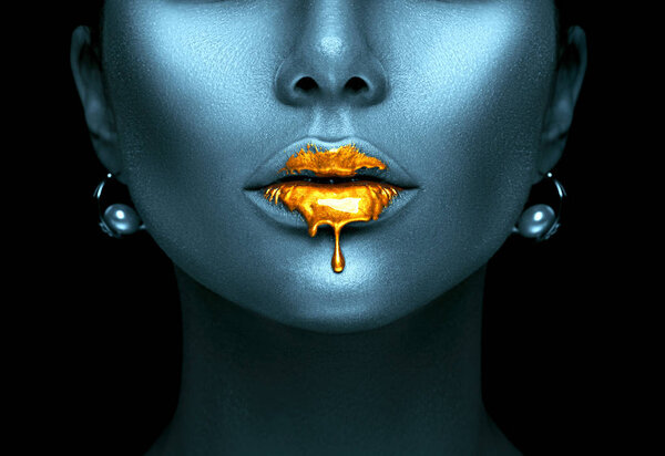 Gold paint drips from sexy lips, golden liquid drops on female mouth, creative abstract skin makeup. Beauty face