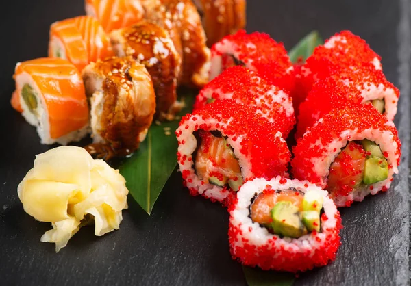 寿司卷特写 餐厅的日式食品 在黑色石板背景上与鲑鱼 蔬菜和飞鱼鱼子酱一起滚动 — 图库照片