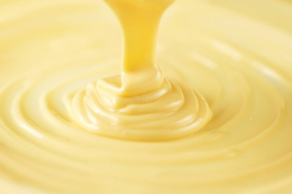 White chocolate. Pouring melted liquid white chocolate. Closeup 