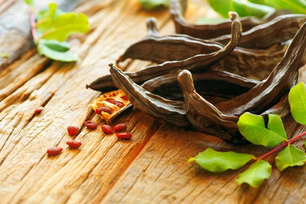 Carob. vainas de algarroba dulce orgánica saludable con semillas y hojas en —  Fotos de Stock