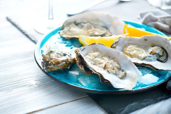 Ostras frescas primer plano en plato azul, mesa servida con ostras , —  Fotos de Stock