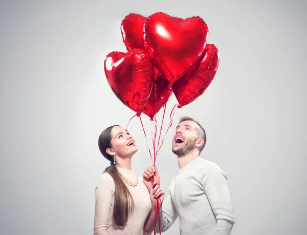 バレンタインデーだ幸せな喜びのカップル 笑顔の美少女とハート型の気球の束を保持している彼女のハンサムなボーイフレンドの肖像画 — ストック写真
